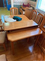 View of the wood laminate dining table with one leaf placed on top, two tablecloths folded on the table, and a padded table protector.