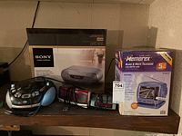 Overview of all electronic items in the lot showing the Sony CD/cassette/radio recorder boxed, Memorex TV boxed, Durabrand boombox, and two clock radios