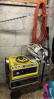 Yellow Suzuki SV2200 generator on wheeled dolly with orange extension cord hanging.