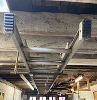 Photo showing full length of aluminum extension ladder mounted horizontally in a garage, highlighting rungs and rubber feet.