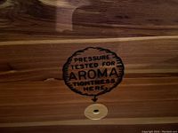 Close-up of interior stamp reading 'Pressure Tested for Aroma Tightness Here' on cedar wood.