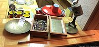 Wide view showing red piston desk lamp, etched metal plate, wooden display box with chain mail and military pins, and other items on table