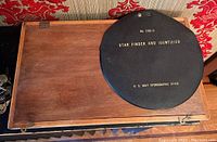 Wooden box with closed lid holding the drafting kit, with black Star Finder on top.
