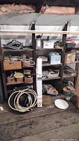 Wide view of 4-level shelf filled with hardware items including coils of wire, boxed miniblinds, tools and accessories.
