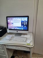 Front view of iMac on desk with wireless keyboard and Magic Mouse.