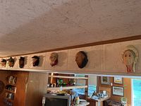 Six Bossons plaster heads mounted on a wall beam in a row, overview of entire set