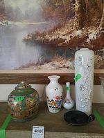 Photo showing the complete lot of five items including the Chinese dragon pot, three vases, and a black decorative dish arranged on a surface with a winter landscape painting behind.