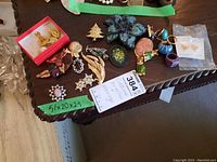 Photo of assorted vintage costume jewelry including several brooches and earrings displayed on a wooden table.