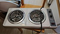Top view showing two coil heating elements and chrome drip trays on a white portable stove