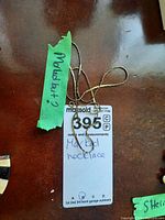 Photo of a green tape indicating 'Marked' with the necklace's lot tag showing 'Marked necklace'.
