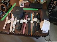 Thirteen watches laid out in two groups on table including a Bulova box at center