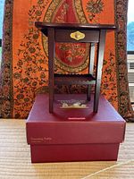 Front view of wooden American Girl Doll Dressing Table resting on original red box with floral tapestry background