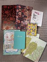 Whole set of 10 blank journals and notebooks showing various sizes and cover styles including floral, owl illustrations, turquoise faux leather, butterfly spirals, and metallic brocade pattern.