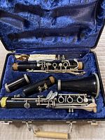 Clarinet disassembled in the blue velvet-lined case showing all parts including bell, lower joint, upper joint, and barrel with silver-colored keys.