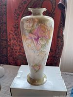 Front view of the tall slender vase with rose pattern and crazing visible on surface.