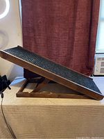 Side view of the wooden dog ramp showing the adjustable incline mechanism and carpeted ramp surface