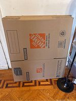 Photo showing flat packed cardboard moving boxes with Home Depot branding and size markings.