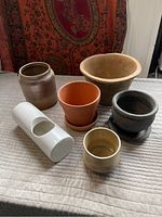 Front view showing all six planters and clay pots arranged on a quilted surface with textile backdrop