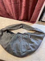 Gray fabric pet carrier laid flat on bed, showing overall shape and material.