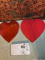 Top-down view of three boxes: red embossed Whitmans heart tin, red quilted fabric heart box, and white rectangular Minnie Mouse tin.