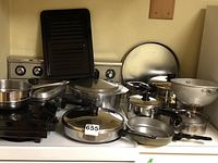 Overview image showing assorted pots, pans, colander, and a griddle on stove