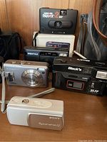 Image showing Sony Cyber-shot U, Fuji FinePix, Black's 35 FF 35mm film camera, Pentax camera, and Micro 110 Panex 2-way film camera