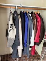 Vintage coats including leather and fabric materials along with a thick knit Cowichan sweater hanging on rack