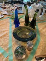 Overall view of the glass decor assortment on table, showing blue and green bird figurines, glass bowl, paperweights, and hobnail vase