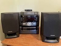 Front view of Sharp component system with two Sharp speakers on wood surface