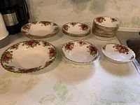 Overall view showing multiple bowls stacked by type on a kitchen counter, displaying floral pattern and gold trim