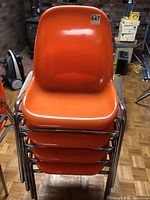 Stacked view looking down on the four dark orange fibreglass chairs showing seat and back