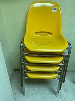 Front view of stacked chairs showing four yellow seats and chrome legs