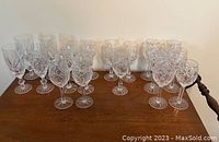 Multiple crystal glasses arranged on wooden surface, showing front view of various sizes