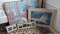 Collection of framed art prints and photograph sets arranged against a wall and on the floor, showing all items together.