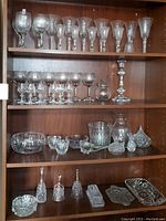 Shelf with multiple crystal stemware wine glasses, goblets, bowl, decorative items