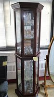 Full view of the dark wood curio cabinet with glass panes and multiple glass shelves, showing various crystal items inside.