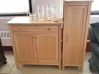 Wide view showing both cabinets side by side, with the sideboard cabinet on the left featuring a drawer and two-door cupboard and the pantry on the right.