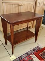 Overall view of the mid-century modern solid wood side table showing front and side angles, highlighting its tapered legs and two-tier design.
