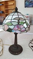 Side view of stained glass lamp showing floral pattern on shade and metal base