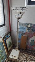 Full view of vintage Fairbanks Morse doctor's scale standing on a patterned rug near framed artwork.