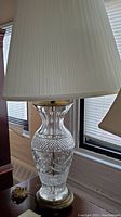 Side view of Waterford crystal lamp showing the pleated fabric lampshade and crystal body with brass base.
