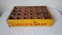 Front view of the wooden bottle crate with 'Virginia Dare' in red lettering on the yellow sides, showing four rows of compartments.