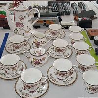 Full 20-piece Wedgwood china tea set displayed with teapot, creamer, sugar bowl, teacups and saucers in floral pattern.