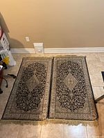 Two black and beige floor runners placed side by side on a tiled floor, showing overall design and size.