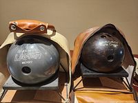 Both Brunswick bowling balls side by side in their carrying bags, showing the Laser and Triple Crown branding.