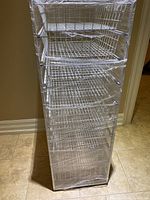 Front angled view of the 8 drawer wire storage unit in white, showing all drawers inside the frame wrapped in plastic.