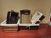 Four wicker baskets of varying sizes displayed on a wooden surface, showing the assortment and fabric linings.
