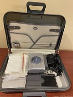 Photo of the card photo printer, power adaptor, multiple photo cards, all inside a black carrying case with organizer.