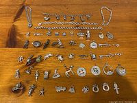 Photo of assorted charms and chain bracelets laid out on wooden surface