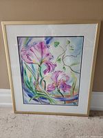 Full view of framed watercolor print of iris flowers with pink and purple petals and green leaves.